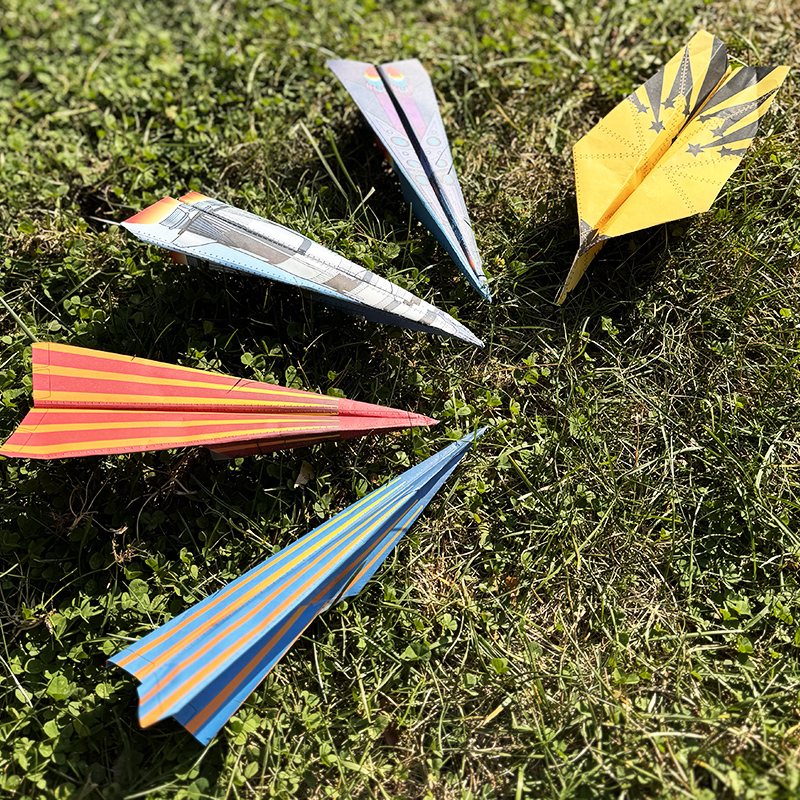 5 paper planes sitting in the grass