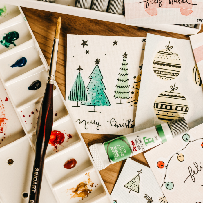 holiday cards with a water color paint design laying on a wood table