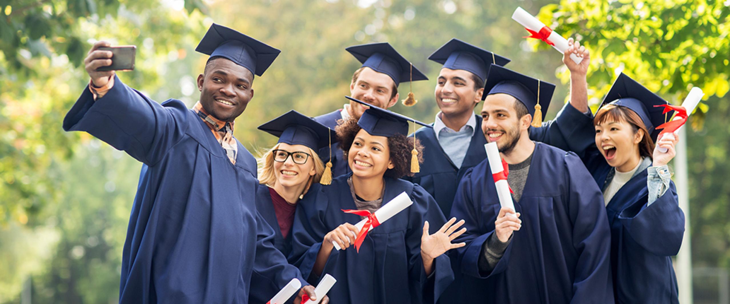 Graduates holding diplomas take selfie