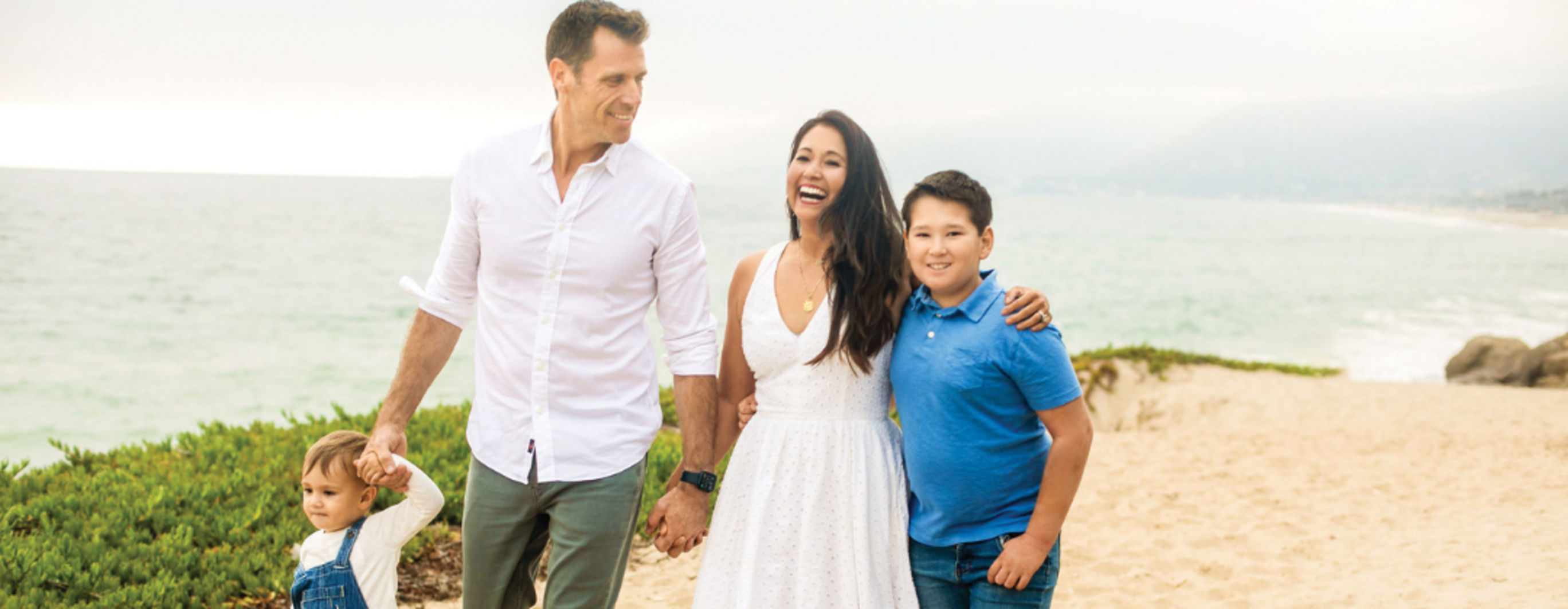 Family of 4 holding hands walking on the beach