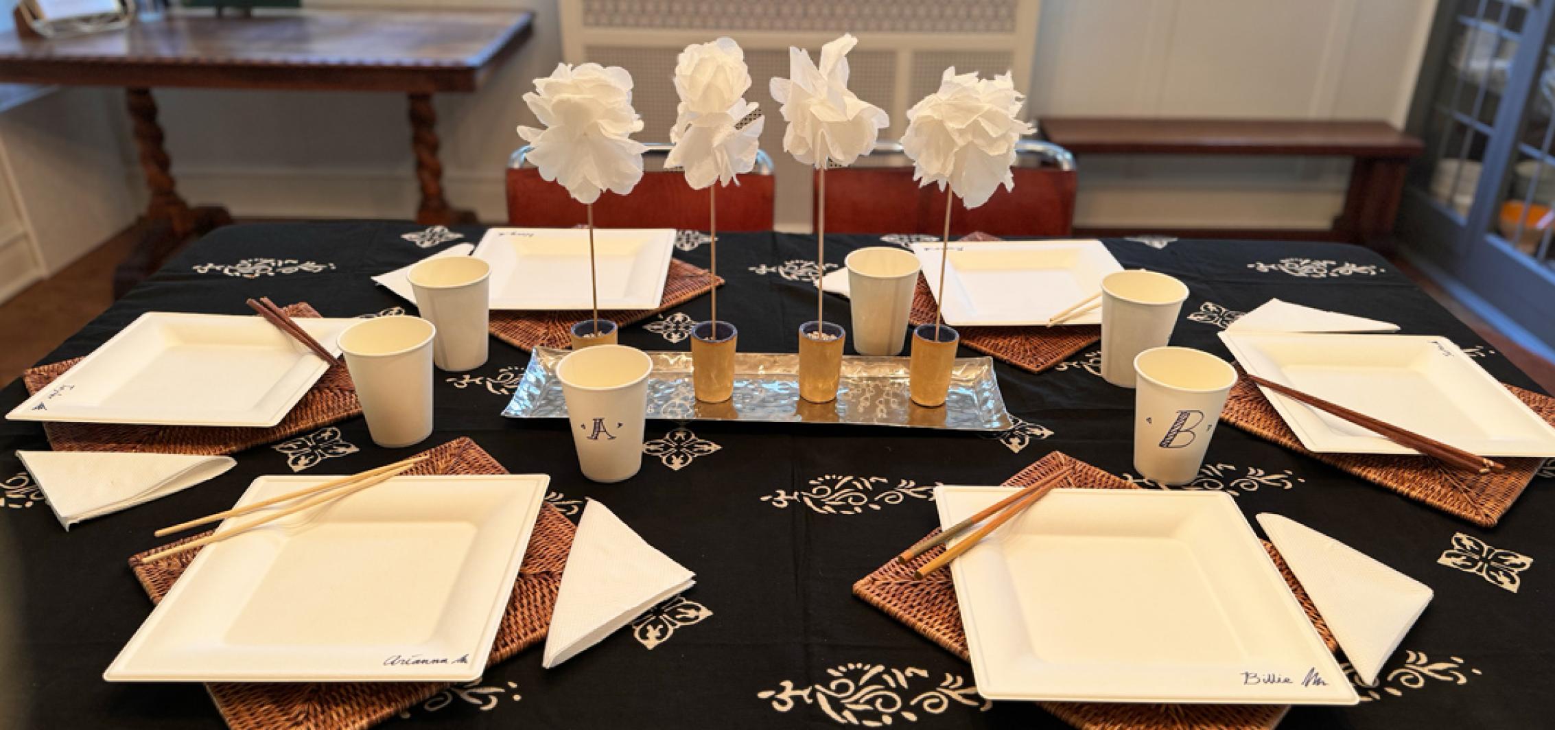 A dinning table set with paper plates, napkins and cups