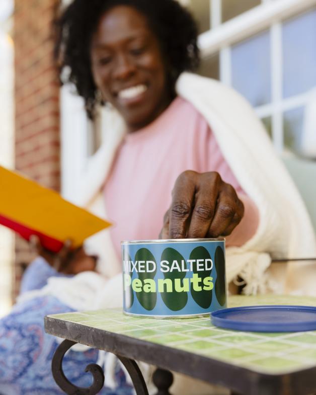 Woman grabbing peanuts out of a paper can.