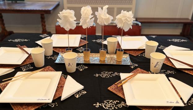 A dinning table set with paper plates, napkins and cups